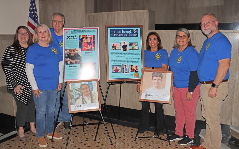 (THOMAS WALLNER | THE GRAHAM LEADER) Members of the Young County Child Welfare Board and Heart Gallery of Northwest Texas stand Wednesday, Oct. 29 next to a Heart Gallery at the Young County Courthouse.