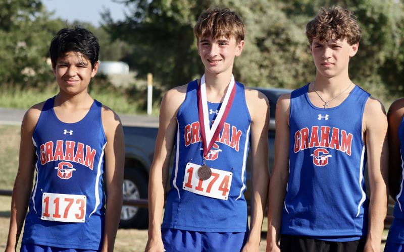 (KYLIE BAILEY | THE GRAHAM LEADER) Kendrick Rivera, left, Nolan Wankowicz, center, and Hudson Weatherman, right, pose for a photo after Wankowicz took home a medal at the Battle of the Back 40 in Poolville. Wankowicz finished 20th in the meet Wednesday, Sept. 17.