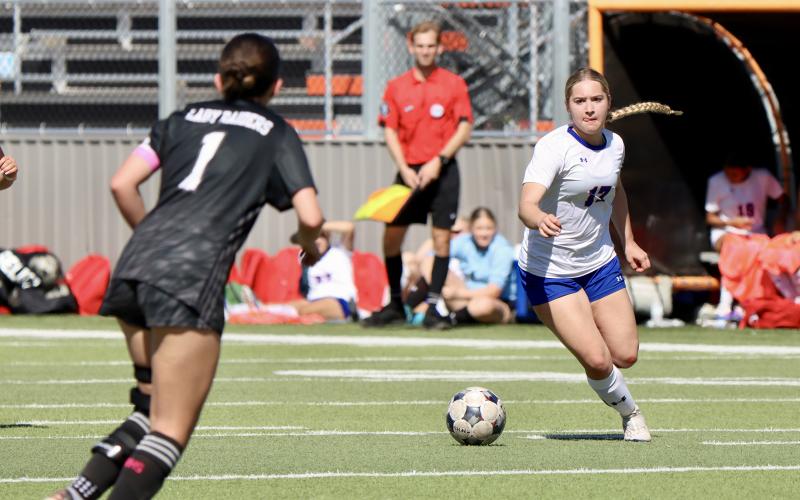 (THOMAS WALLNER | THE GRAHAM LEADER) Adi Pinkston moves the ball down the field while being watched by an opponent of Canyon Randall Lady Raiders. The Lady Blues were bi-district champions after their win Thursday, March 19 over the Lady Raiders.