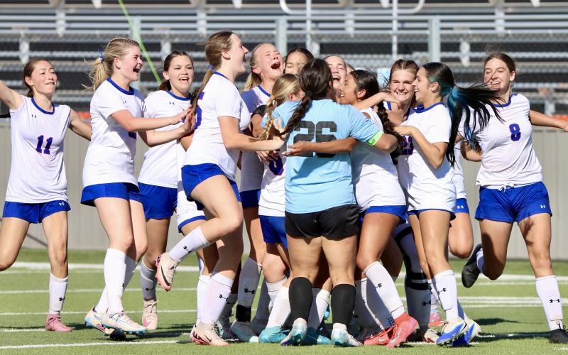 (THOMAS WALLNER | THE GRAHAM LEADER) The Lady Blues rush the field to hug goalie Taylor Lauster and Ellie Weatherman, who secured the final goal in a penalty shootout during the bi-district matchup Thursday, March 19.