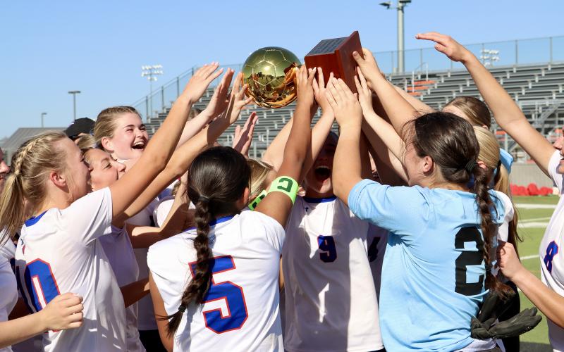 (THOMAS WALLNER | THE GRAHAM LEADER) The bi-district championship trophy is held high in the air as the Lady Blues celebrate their victory Thursday, March 19 over the Canyon Randall Lady Raiders. The next round for the Lady Blues was against the Lubbock-Cooper Lady Patriots in area.