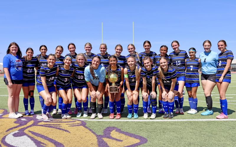 (THOMAS WALLNER | THE GRAHAM LEADER) The Lady Blues pose with their area championship trophy after their 1-0 win Tuesday, March 24 over the Lubbock-Cooper Liberty Lady Patriots at Sandifer Stadium in Abilene. The team advanced to the regional semifinal round held Friday, March 27.