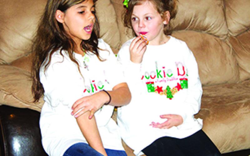 Emma Bratcher (left), 9, holds a conversation with her cousin, Kayleigh Sams, 8, at the annual Cookie Day celebration Friday afternoon at the home of Graham resident Mary Braddock. Both of the girls are great-granddaughters of Braddock, who makes thousands of cookies each year to provide for free to hundreds of Graham residents who attend Cookie Day.