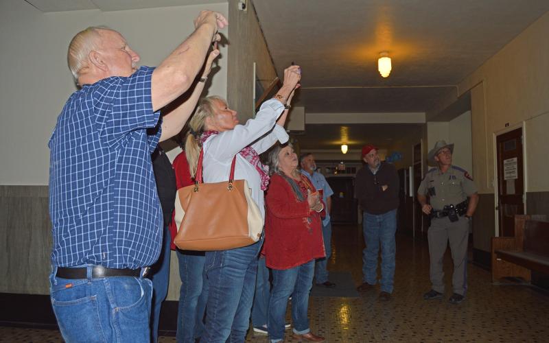 (THOMAS WALLNER | THE GRAHAM LEADER) Visitors at the Young County Courthouse take photos of a television screen displaying the early voting results of the Young County Judge race between Republican candidate Win Graham and write-in candidate Joe Finfrock.