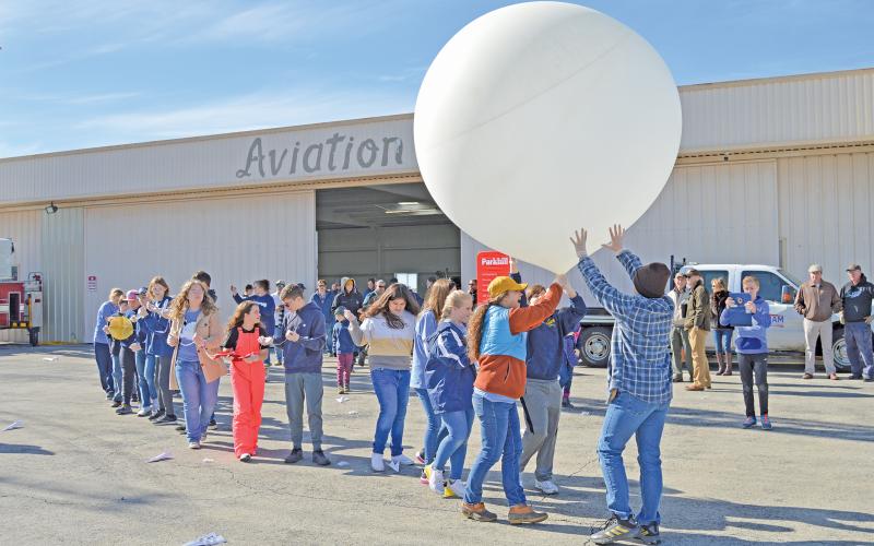 (THOMAS WALLNER | THE GRAHAM LEADER) Open Door Christian School students transport a high-altitude balloon out of a hangar at Graham Municipal Airport before launching it on Saturday, Nov. 12. The balloon traveled from Graham to Keller and was later recovered by a team of students and adults at the location.