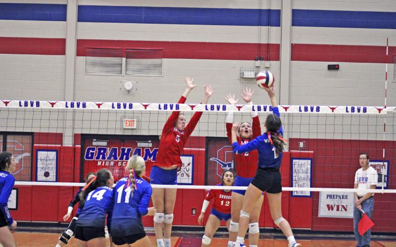 (MIKE WILLIAMS | THE GRAHAM LEADER) Braylee Mayes (5) and Tatum Westerman attempt a block at the net during the first set of the Lady Blues' 3-2 victory over Windthorst Tuesday evening at Graham High School.