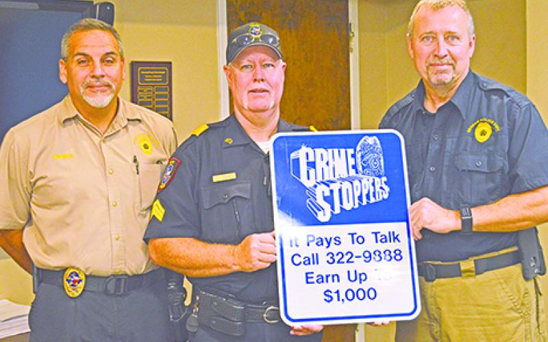 Graham Police Chief Tony Widner (left) with Sgt. Chris Denney (right) and Sgt. Bj Cook as they present a sign for the Crime Stoppers program that will be placed throughout Graham. 