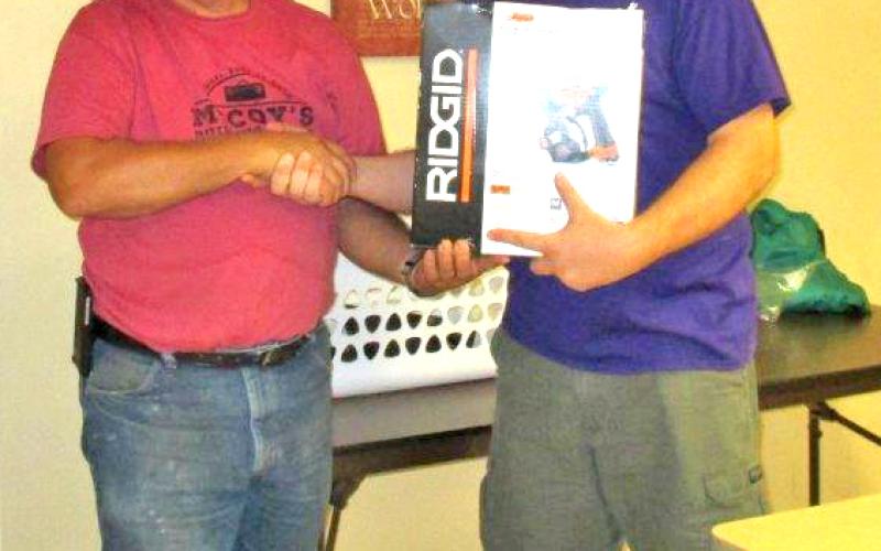 Terry Crain, United Methodist Committee on Relief construction manager, is presented with a new nail gun by Rev. Michael Cyr, pastor of First United Methodist Church of Newcastle.
