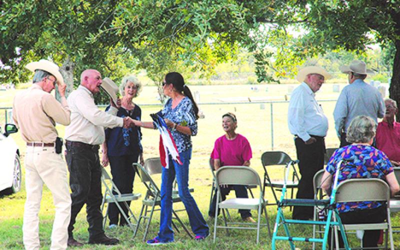 Robyn Fontenot shakes hands with retired Texas Ranger Phil Ryan, while retired Ranger Dick Johnson, left, looks on, during the gathering before the dedication of a special Ranger Memorial Cross at the grave of Fontenot’s ancestor, Charles Lemuel Ray. Between Fontenot and Ryan is Kay Dosher, whose genealogical research led to the discovery that Ray and his brother both were rangers in 1874-75.
