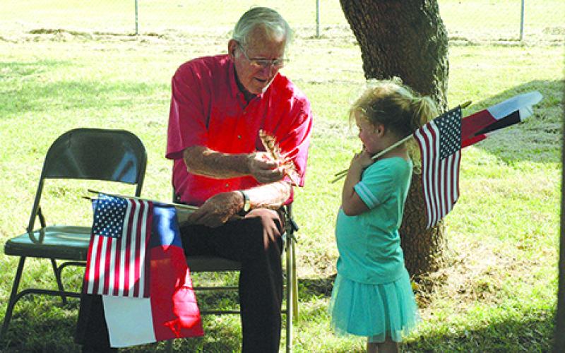 Orville Dunsworth, of Oklahoma City, hands a hawk feather to Lacie Dosher, 4, prior to a dedication ceremony of a Texas Ranger Memorial Cross at the grave of their ancestor, Charles Lemuel Ray, at Farmer’s Cemetery in northern Young County.