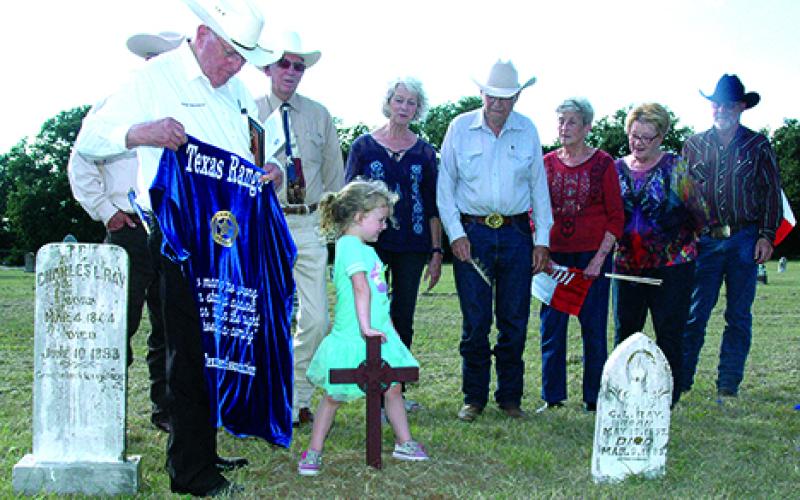 Lacie Dosher, center, places her hand on the Texas Ranger Memorial Cross just unveiled by retired Ranger Ralph Wadsworth at Farmer’s Cemetery in northern Young County. The cross honors Charles Lemuel Ray, who served in the Rangers 1874-75. His gravestone is at left.  Leader photo by Brenda Sommer