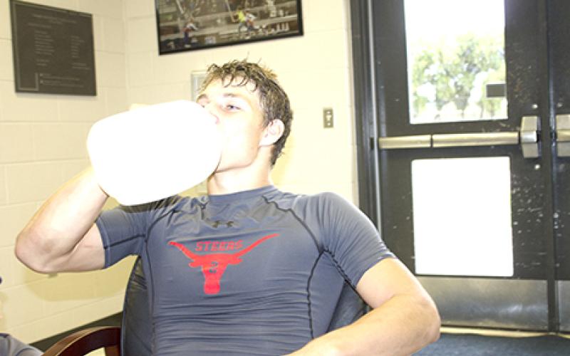 Chase Crawford took a gulp from his gallon jug of water during a break Tuesday morning. The gallon-a-day rule is in effect from the first day of practice, and it forces kids to get the necessary amount of water to stay hydrated.			