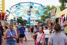 (THOMAS WALLNER | THE GRAHAM LEADER) Visitors walk down the inside of the square near the corner of Second Street and Oak Street past games and rides at the Lions Club Carnival in 2025. The carnival will be returning downtown May 7-9 with food and more.