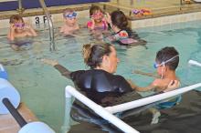 (THOMAS WALLNER | THE GRAHAM LEADER) Tracey Terasas helps teach a preschool student from Pioneer Elementary School how to kick their feet to swim Wednesday, April 5.