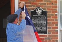 (THOMAS WALLNER | THE GRAHAM LEADER) Young County Historical Commission member Eric Clifton unveils the 1921 Young County Jail historic marker during a dedication ceremony Saturday, Oct. 7.