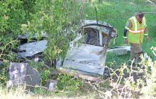 (THOMAS WALLNER | THE GRAHAM LEADER) A first responder walks around a vehicle involved in a wreck Saturday, April 13 on Hwy. 16 South near Salem Loop. The vehicle left the roadway and crashed into the trees near the road.