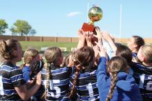 (ARCHIVE PHOTO | THE GRAHAM LEADER) The Lady Blues lift the bi-district trophy up and celebrate together after defeating Borger in a bi-district matchup Monday, March 25. The win was the Lady Blues’ first playoff victory in the program’s history as they beat the Lady Bulldogs 4-3 in a penalty kick shootout.