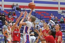 (THOMAS WALLNER | THE GRAHAM LEADER) Katy McGeehee of the Lady Blues jumps over Mineral Wells defenders as she attempts a shot Friday, Jan. 17. The Graham team picked up its first district win during the midpoint of their schedule.