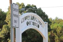 (THOMAS WALLNER | THE GRAHAM LEADER) The entranceway to the Oak Grove Colored - William P. Johnston Cemetery along with a sign showing parking at the cemetery. A ground penetrating radar survey found 14 possible unmarked graves in the city of Graham-owned cemetery parking area.