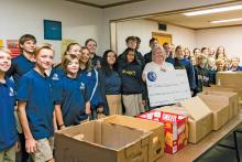 (CONTRIBUTED PHOTO | HANNAH ATWOOD) Students from Open Door Christian School pose with a check presented to Graham Backpack Buddies for $585. Shown in front of the students are over 1,000 food items donated for the local program.