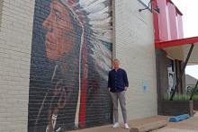 (THOMAS WALLNER | THE GRAHAM LEADER) Local artist Gaven Henderson stands next to a partially completed mural at the Young County Museum of History and Culture. The mural is one of five he will complete for the wall of the museum.