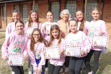 (THOMAS WALLNER | THE GRAHAM LEADER) Members of Coco Candy Canes pose for a photo with a member of their benefiting nonprofit Our Daily Bread. Team members are Reagan Figg, McKenna Bussey, Kynlee Besack, Bailey Kilpatrick, Kaitlyn Leach, Hattie Stephens, Harper Shaffer, Maddox Shaffer, Harper Hampton and Emmalyn Atkins.