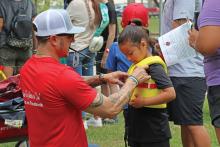 (ARCHIVE PHOTO | THE GRAHAM LEADER) Aaron Terasas fits a life jacket for a visitor of the 2024 Family Fun and Fishing event at Firemen’s Park. There will be a limited number of life jackets available at the event due to another life jacket giveaway event being held in the summer.
