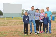 (THOMAS WALLNER | THE GRAHAM LEADER) The McFerrins pose for a family photo in front of the Graham Drive In theater which they are taking over officially at the beginning of April. Shown from left to right are Cruz, Chip, Jett, Brandi, Cash and Mason McFerrin.