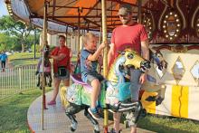(FILE PHOTO | THE GRAHAM LEADER) Visitors to the Graham Lions Club Carnival in 2022 ride the merry-go-round located on the empty lot at Second Street and Oak Street inside the downtown square. The carnival this year will be held nightly from May 10-13 on the downtown square.