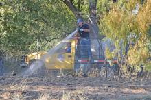 (MADDISON EVANS | THE GRAHAM LEADER) A member of the Loving Volunteer Fire Department sprays a burnt patch of grass off FM 61 in Young County Wednesday, Sept. 28. As of Thursday afternoon, the fire was reported as 100% contained.