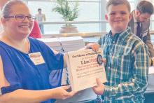 (CONTRIBUTED PHOTO | NISD) Programs Manager for Texas Congress of Parents and Teachers (PTA), Carrie Mays, presents Newcastle Elementary student Leon Creel with a certification of publication for his short story ‘Raid on the Creek’ included inside the worlds largest book ‘I Am Texas.’