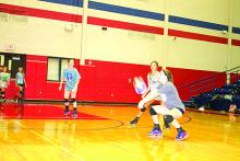 Left, Aubree Beggs watches as Emily Schaefer makes a pass during Monday drills at the Lady Blues’ first practice of the season. The Blues made it to the second round last year before falling to Decatur.	